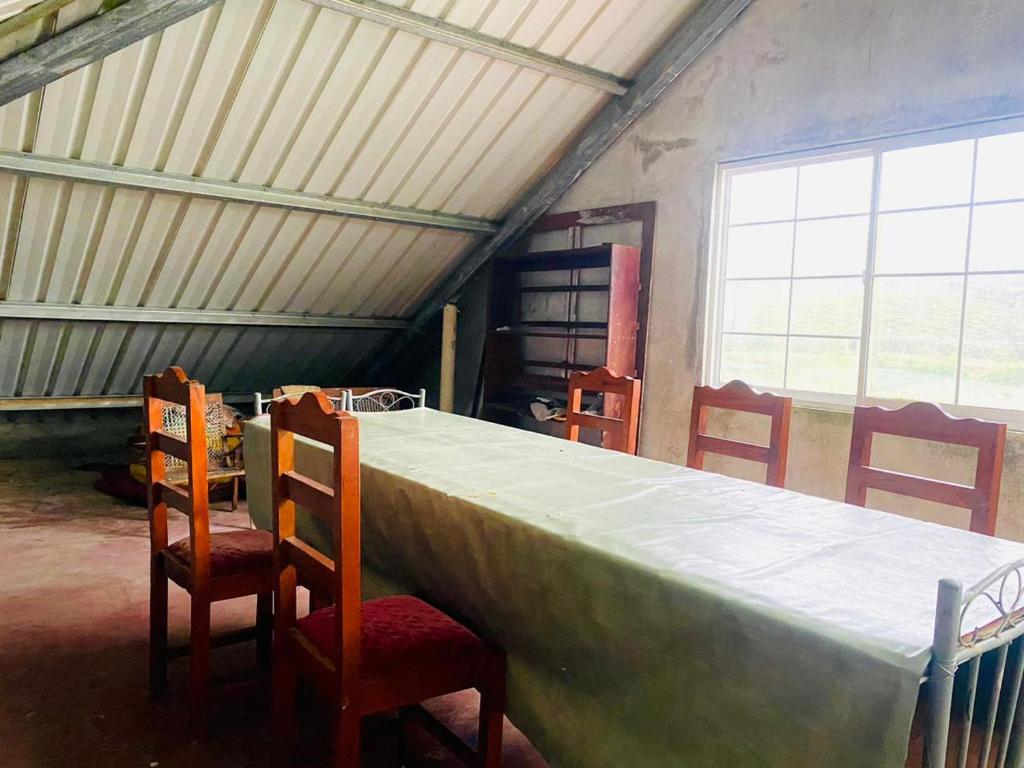 a room with a large table with chairs and a window at Siloneeds HOSTEL in Nuwara Eliya