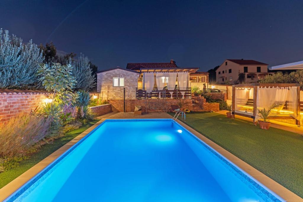 a swimming pool in the backyard of a house at night at Villa Nicoletta in Polača