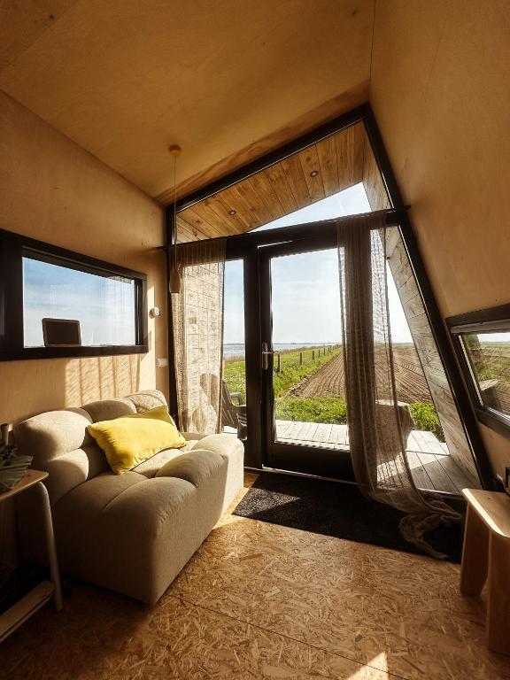 a living room with a couch and a large window at Slapen op de Dijk - Tiny House in Kraggenburg