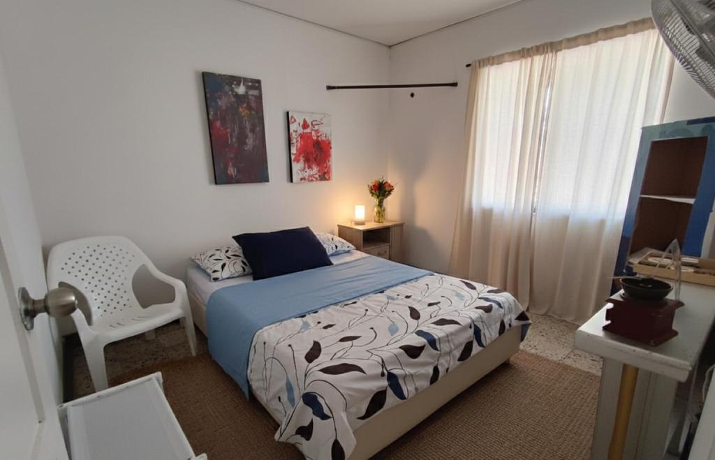 a bedroom with a bed and a chair and a window at Habitacion privada y central in Barranquilla