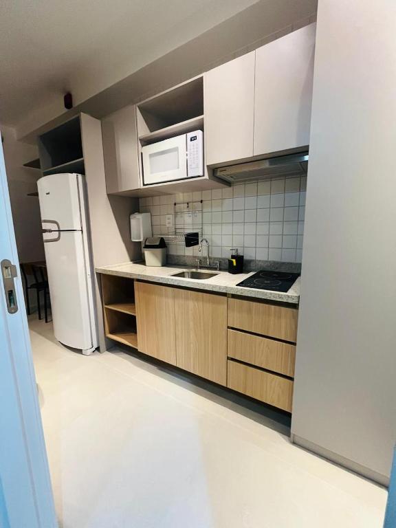 a kitchen with white cabinets and a white refrigerator at Apto Stúdio Liberdade novíssimo in São Paulo