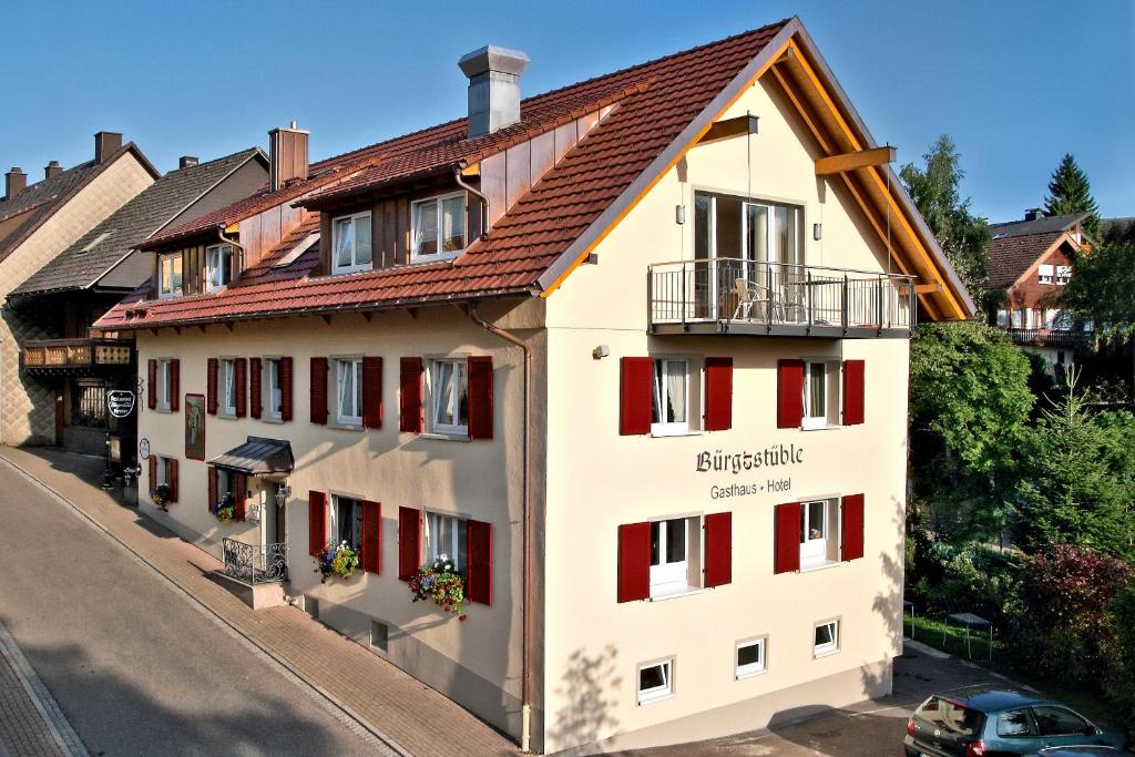 a white building with red shutters on a street at Bürgerstüble in Sankt Peter