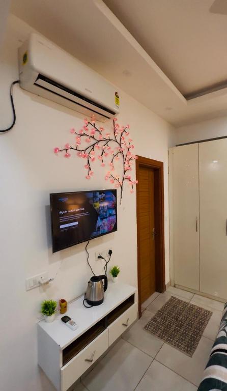 a living room with a tv and a tree on the wall at The dream studio in Noida