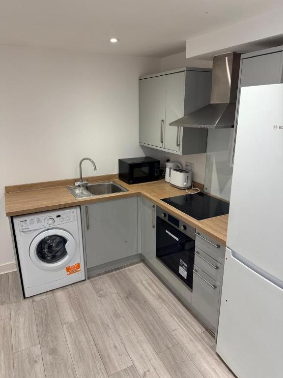 a kitchen with a washing machine and a sink at Epsom High Street Apartment 6 in Epsom