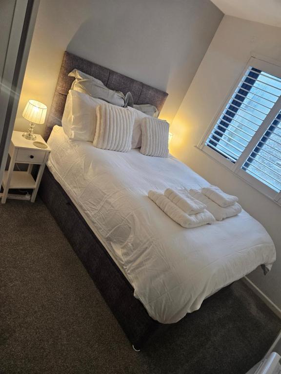 a bed with white sheets and pillows and a window at Flat 8 in Plymouth