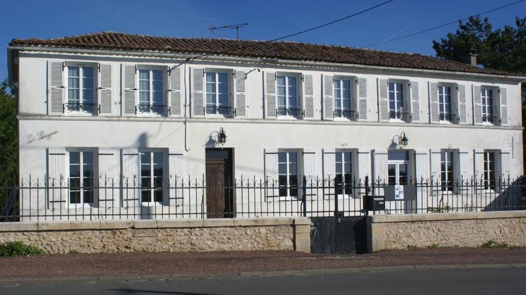 a white building with a fence in front of it at La bergerie in Chaillevette