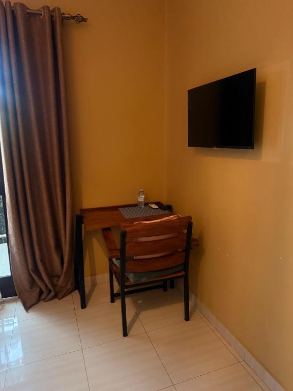 a dining room table with a chair and a television on the wall at May 7 in Soroti