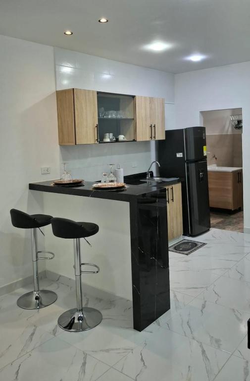 a kitchen with a black counter and two bar stools at Apartamento en Roldanillo in Roldanillo