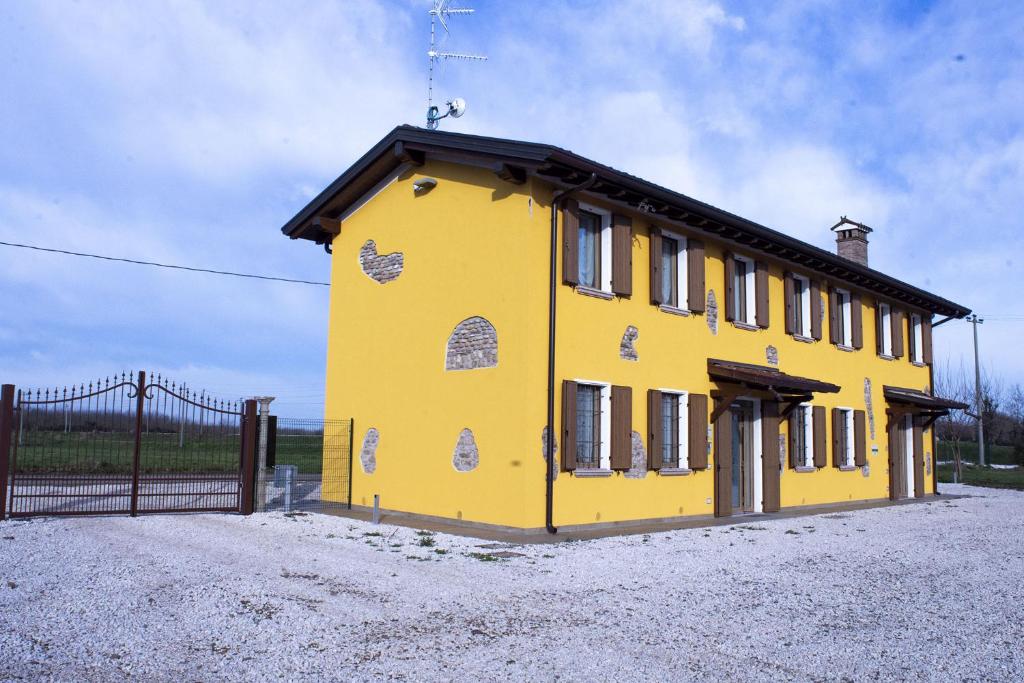 a yellow building with a black roof next to a fence at Gaspari Farm Relais in Volta Mantovana