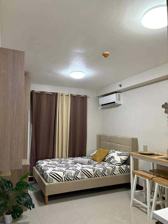 a bedroom with a bed with a curtain and a table at Studio Stay at Saekyung Condominium in Lapu Lapu City