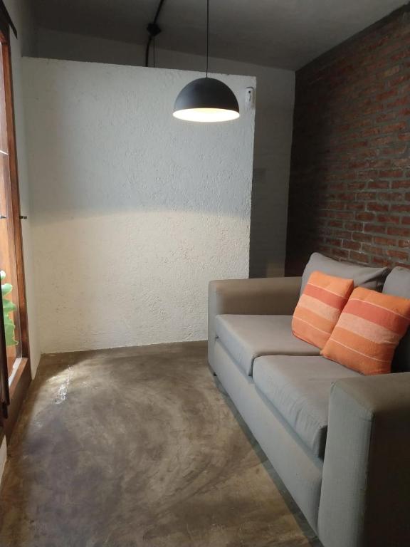 a living room with a couch with two orange pillows at Hospedaje JosEva in Unquillo