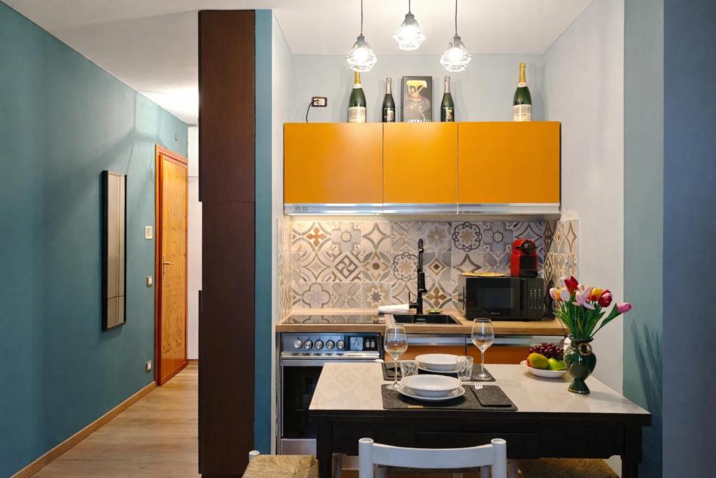 a kitchen with yellow cabinets and a table with flowers at Hostdomus - Petit Bleu in Cesana Torinese