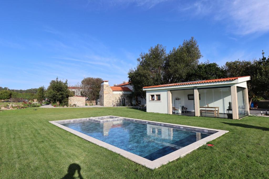 a shadow of a person standing in the grass next to a swimming pool at Quinta das Aromáticas in Malta