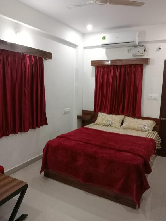 a bedroom with a large bed with red curtains at KSM Rooms in Tiruvannāmalai