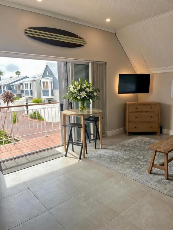 a living room with a television and a table with flowers at Luxurious Loft on Spinnaker! in Knysna