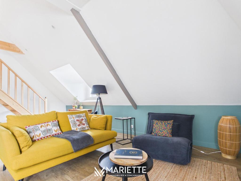 a living room with a yellow couch and a chair at -LE CHALET- Joli cocon au centre de Concarneau in Concarneau