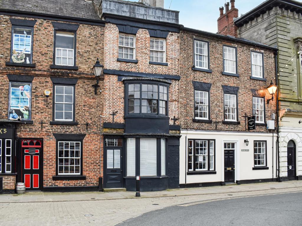 a brick building with a red door on a street at Market Place View in Knaresborough