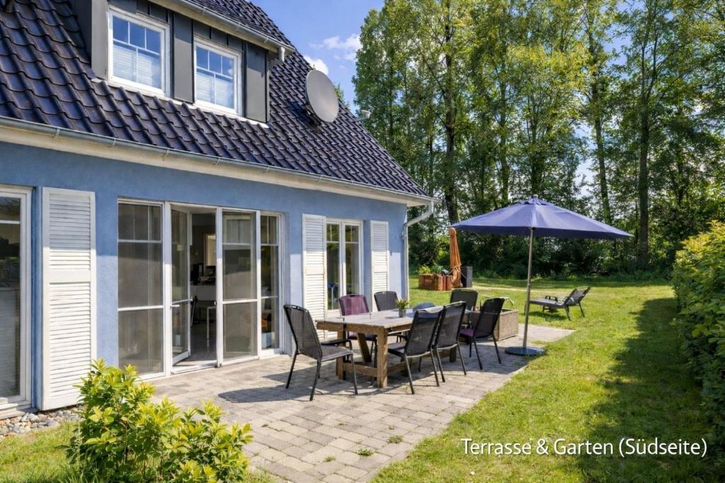 a patio with a table and chairs and an umbrella at Villa Mara - für 12 Gäste, Sauna, 1 Wirlwanne, 2 Duschen, Kamin, 5 SZ, 3 WC, Highspeed Internet, abgezeuntes Grundstück in Glowe