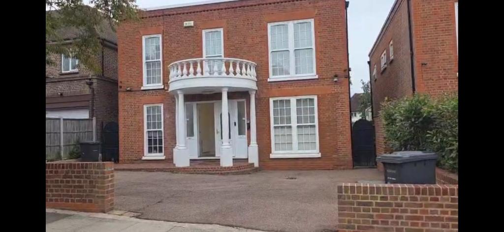 a brick house with a white porch and a balcony at First Class Luxurious Apartment London Finchley in Brent Station