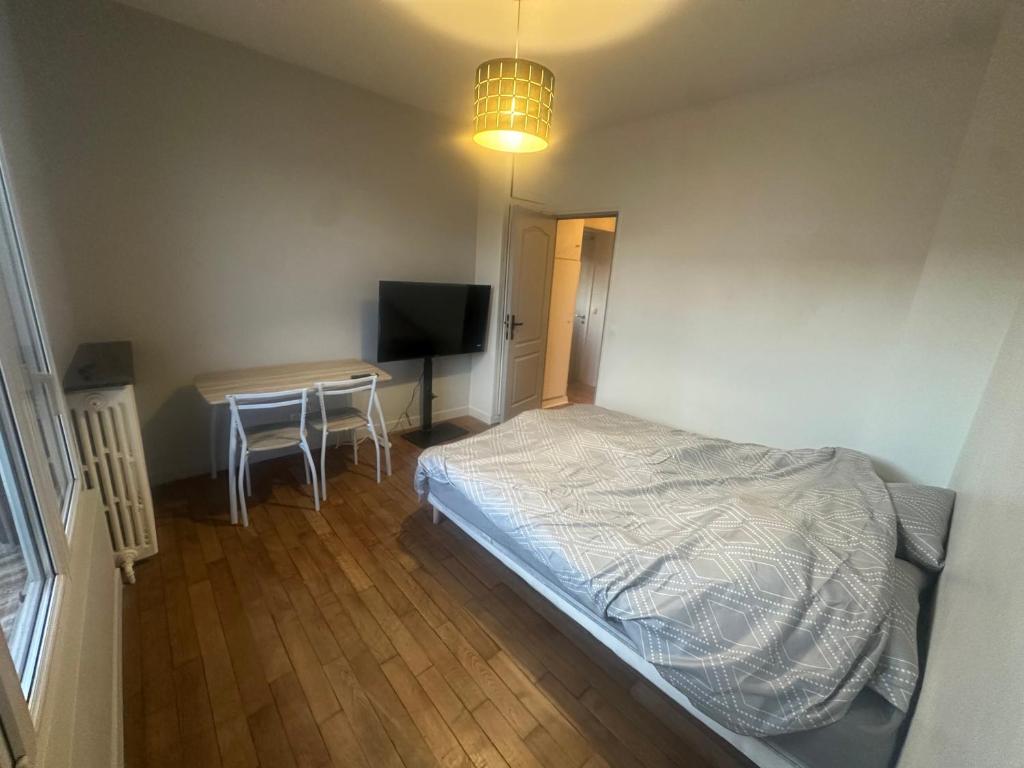 a bedroom with a bed and a desk with a television at Chambre privee dans une maison 2 in Aulnay-sous-Bois