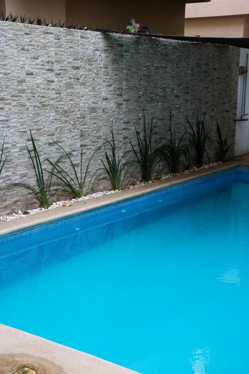 a swimming pool in front of a brick wall at Departamentos Perfectamente ubicados con alberca in Ciudad Madero