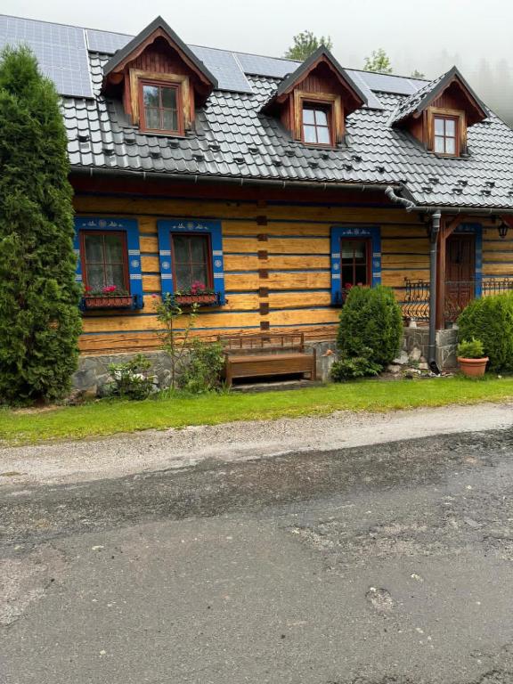 a wooden house with a bench in front of it at Goralska Chalupa in Vígľaš