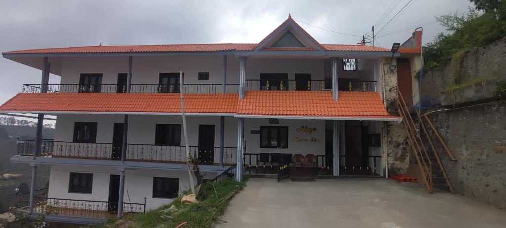 a white house with an orange roof and a balcony at AFIYA HOME STAy in Kodaikānāl