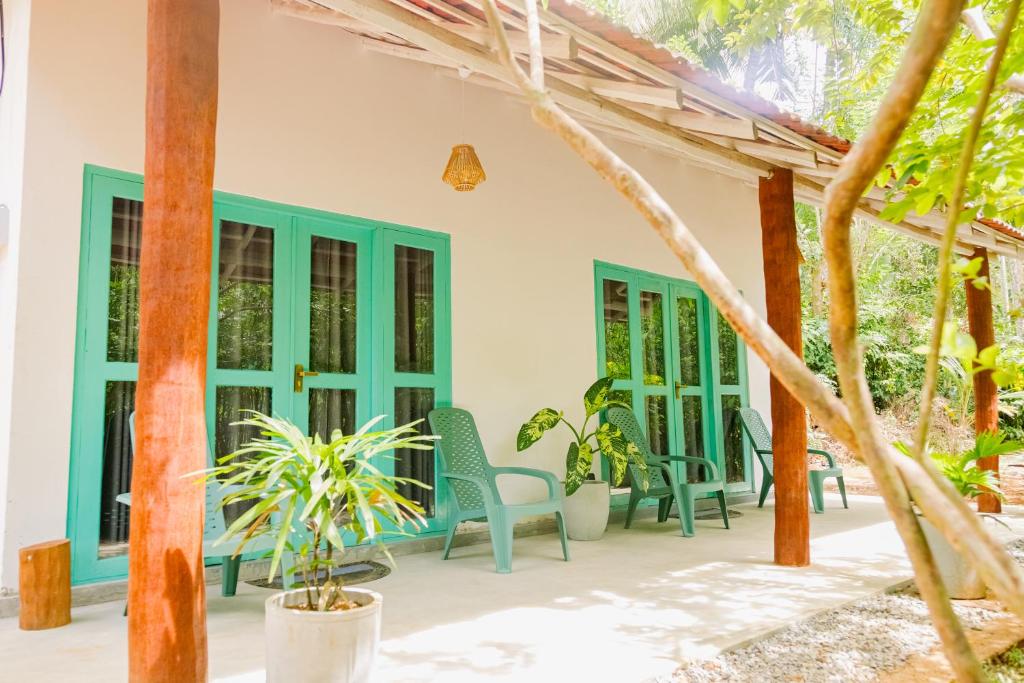 a patio of a house with chairs and trees at Lazy Monkey Green Chalets in Hiriketiya
