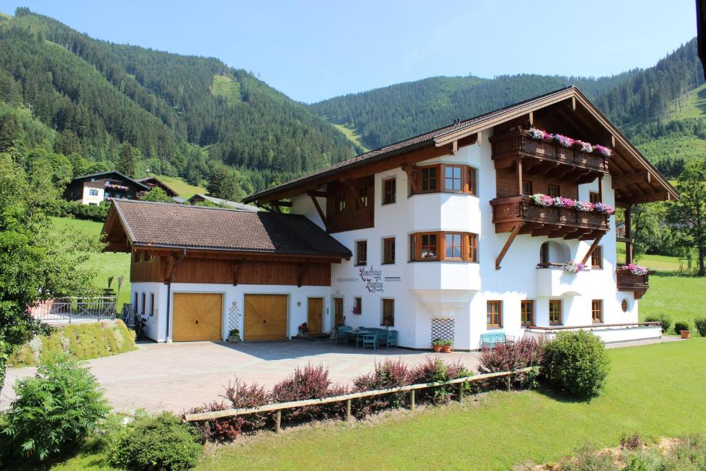 a large white house in a field with mountains at Landhaus Zaglauhof in Werfenweng