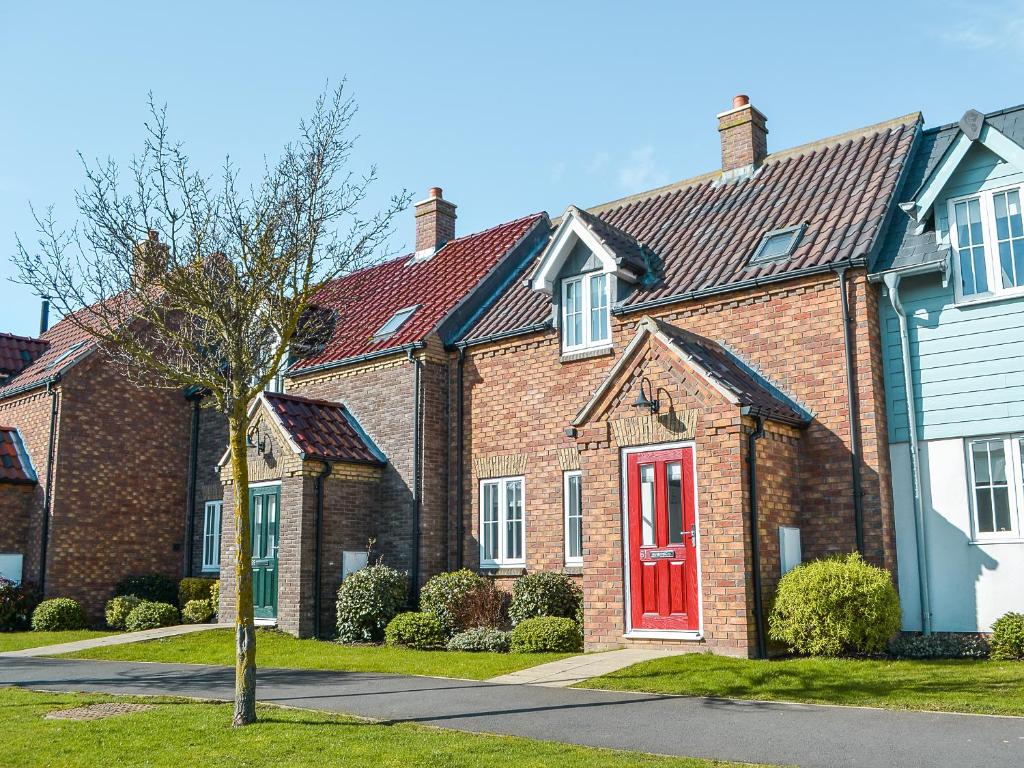 a large brick house with a red door at Pine View Cottage in Filey