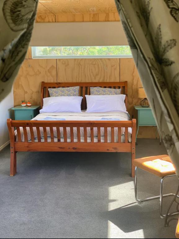 a wooden bed in a room with two night stands at Tree House Jan Juc in Torquay