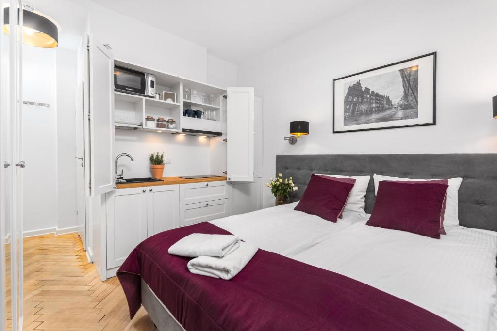 a bedroom with a large white bed with purple pillows at AURA 77 Żoliborz in Warsaw