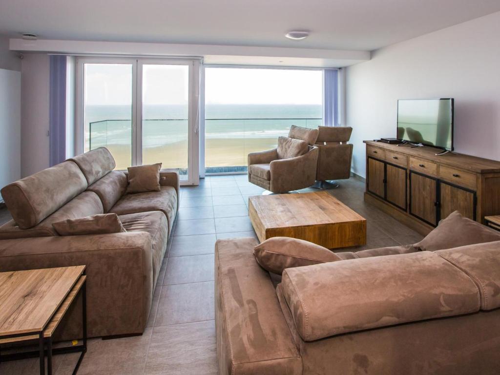 a living room with couches and a television and the ocean at Les Amiraux - 0701 + box 2 in Westende-Bad