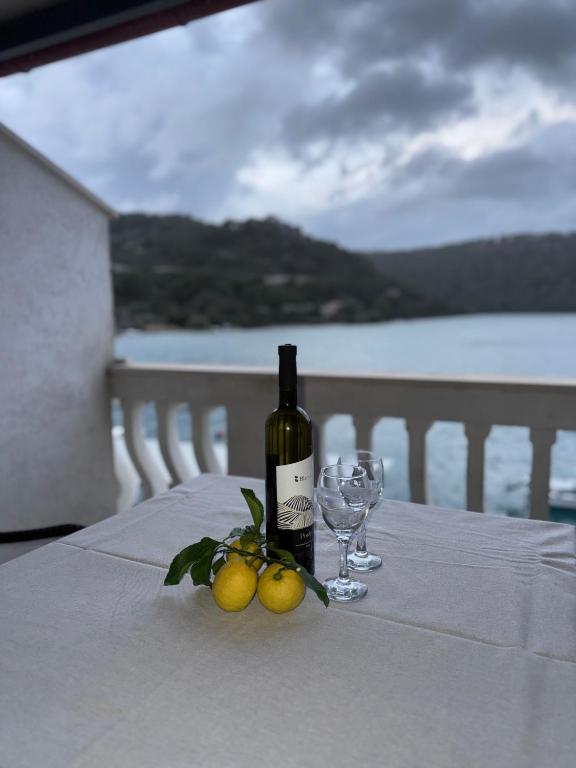 a bottle of wine and two glasses on a table at Apartment Anka Polače in Polače