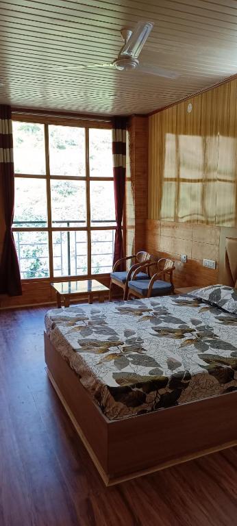 a bedroom with a large bed in a room with windows at Apple Bud Homestay in Ghund