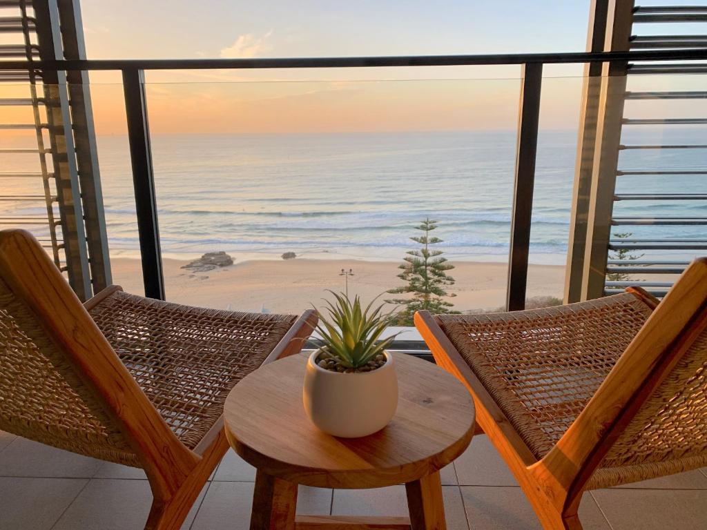 a table and chairs on a balcony with a view of the beach at Coastal Luxe - Eats, Walks, Swims - 1 Car in Newcastle