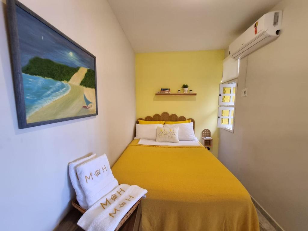 a small bedroom with a yellow bed and a painting at Espaço do acalanto- Quarto em apartamento compartilhado in Natal