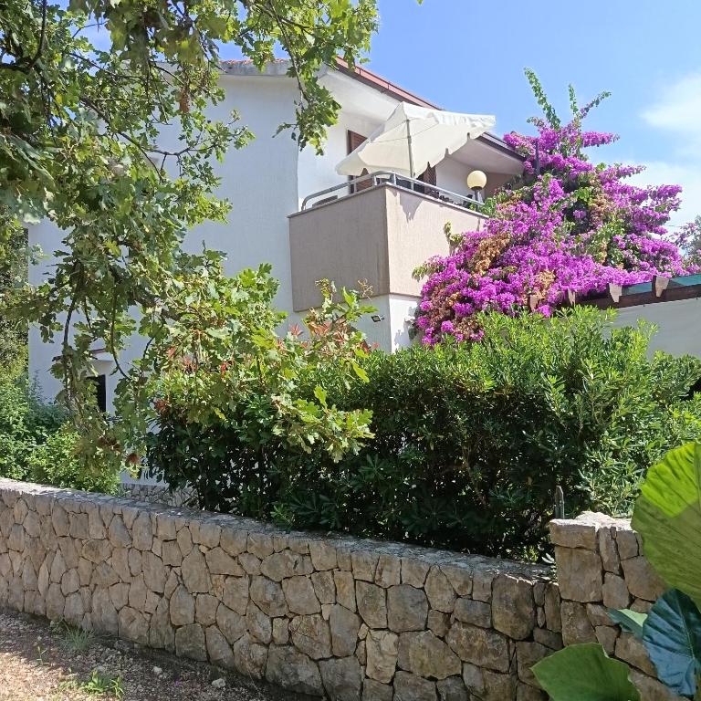 una casa con fiori e un muro di pietra di Apartments Barbara a Pinezići