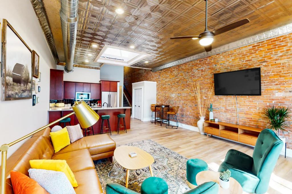 a living room with a couch and a brick wall at 'Downtown Delight' w/ Patio! 1 Mi to Ball State in Muncie