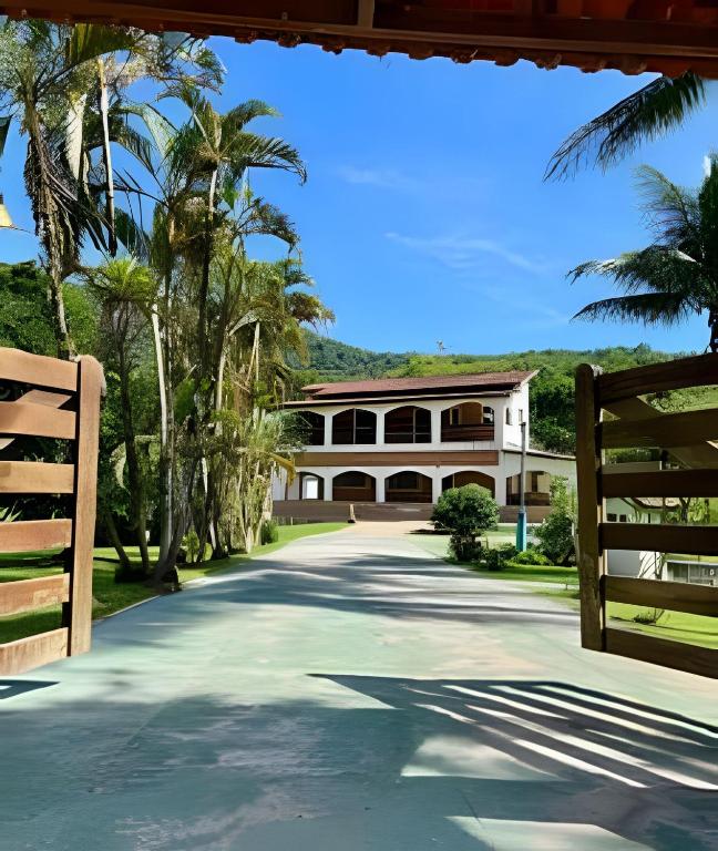 a large house with palm trees and a driveway at Refúgio na natureza com piscina e churrasqueira in Pedro de Toledo