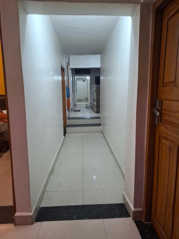 a hallway with a white wall and a door at Vatika palace in Ayodhya