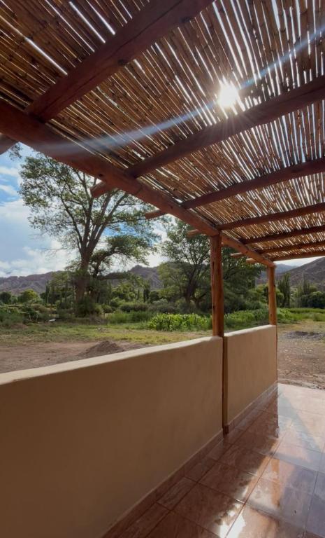 a wooden pergola with a view of a field at Casa campo Ayllu in Tilcara