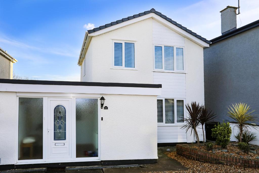 a white house with a garage at Penrhos Walks in Holyhead