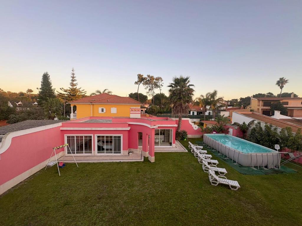 a pink house with a swimming pool and chairs at Verdizela Suites in Corroios