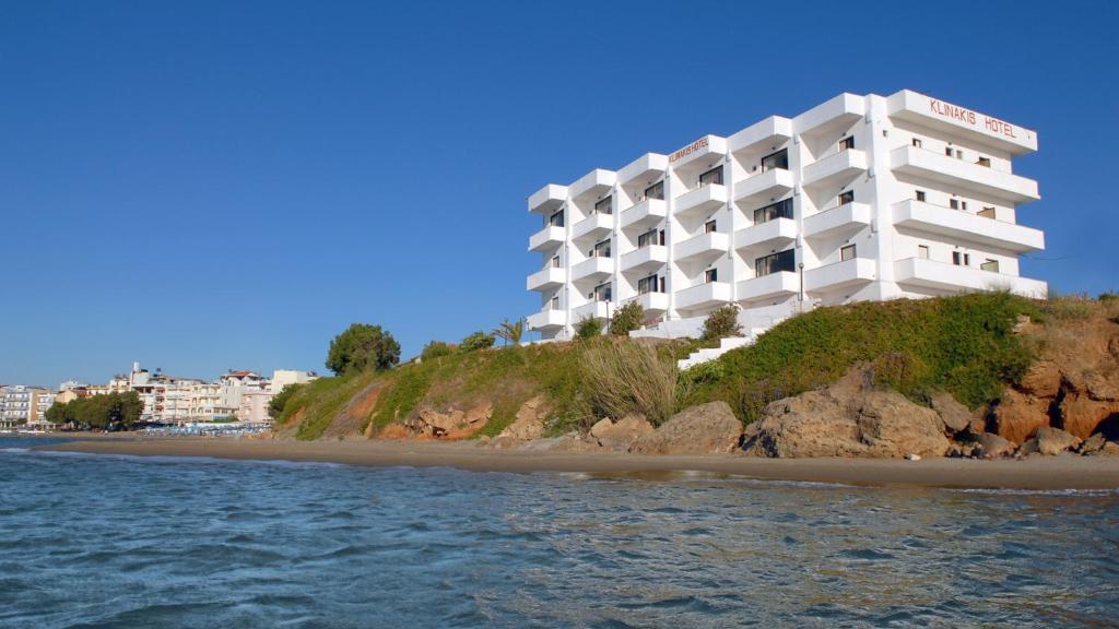 a white hotel on a hill next to a beach at Klinakis Beach Hotel in Chania