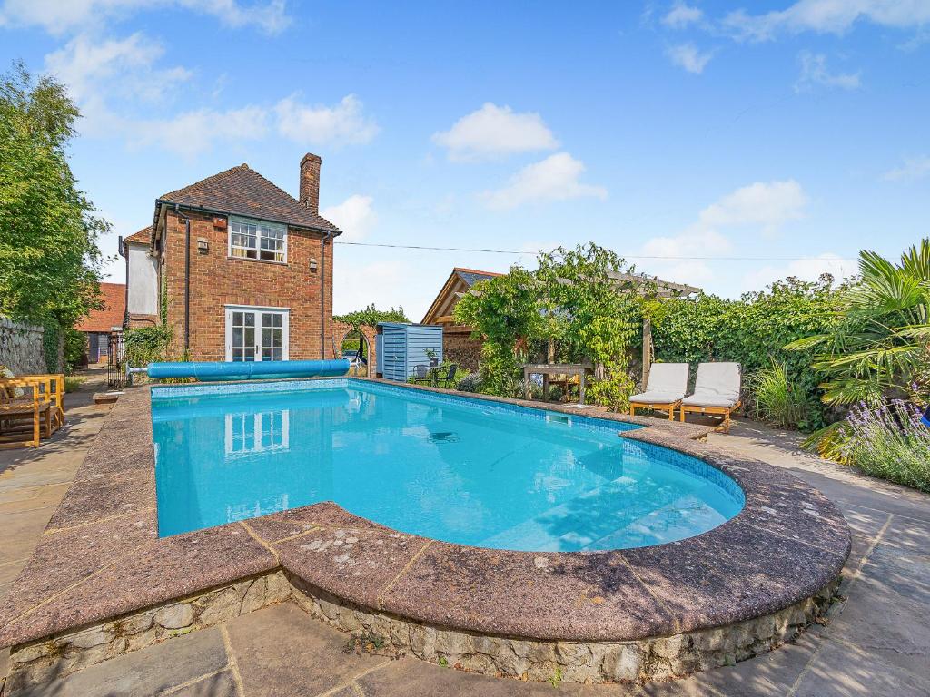 a large blue swimming pool in front of a house at Swallow - Uk50155 in Faversham
