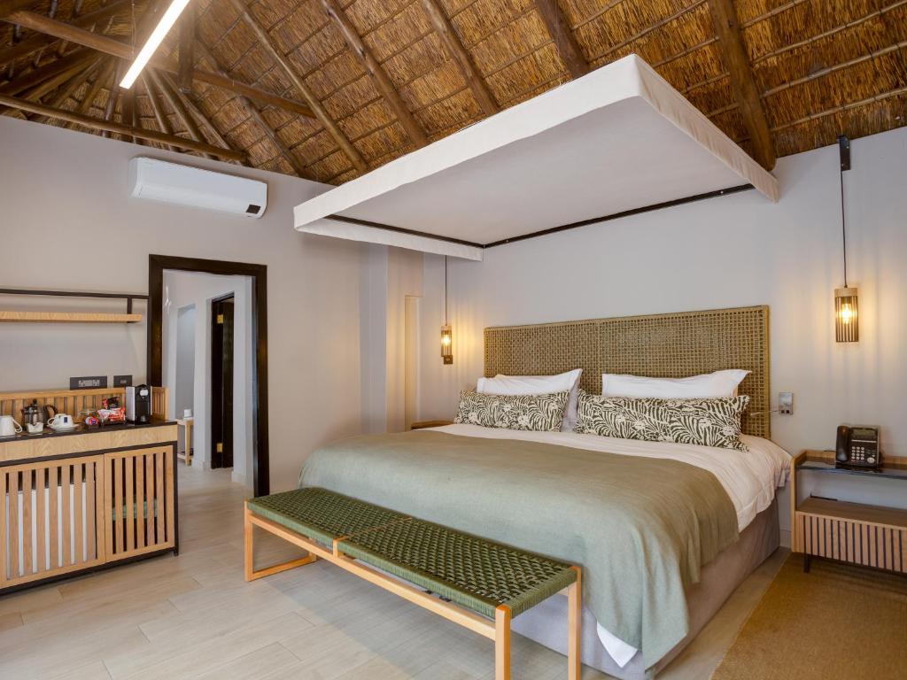 a bedroom with a large bed and a wooden ceiling at Ivory Tree Game Lodge in Pilanesberg