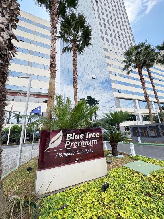 a sign in front of a building with palm trees at Blue Tree Premium Alphaville in Barueri