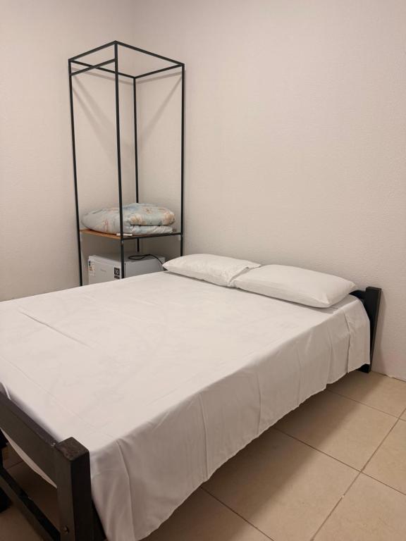a bed with white sheets and a metal frame at Hostel em Jaguarão in Jaguarão