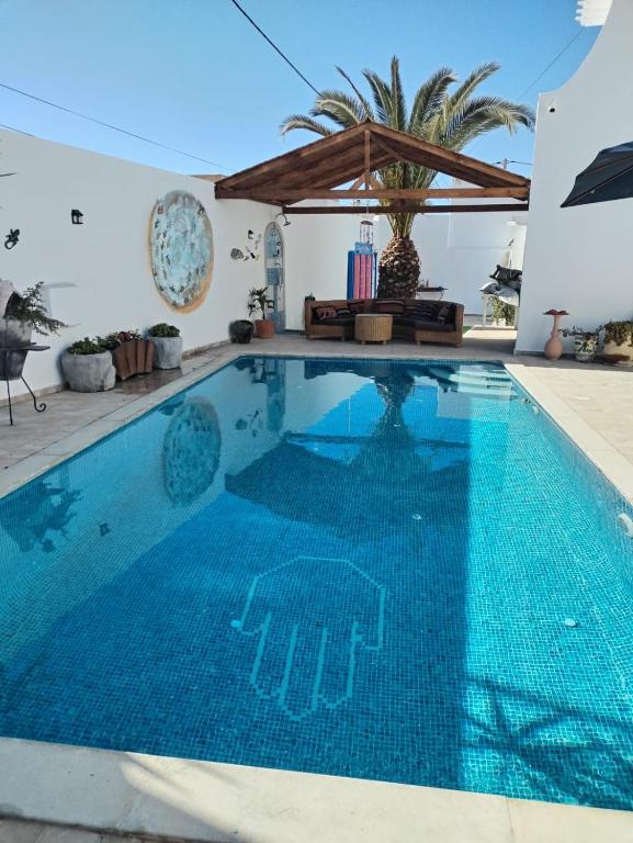 a swimming pool in a villa with a blue pool at Dar Cally Maison d Artiste in Midoun